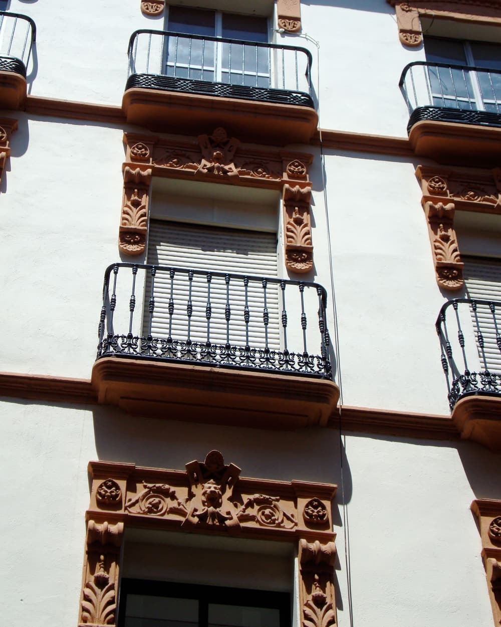 Fachada de un edificio de viviendas con balcones de hierro forjado y persianas